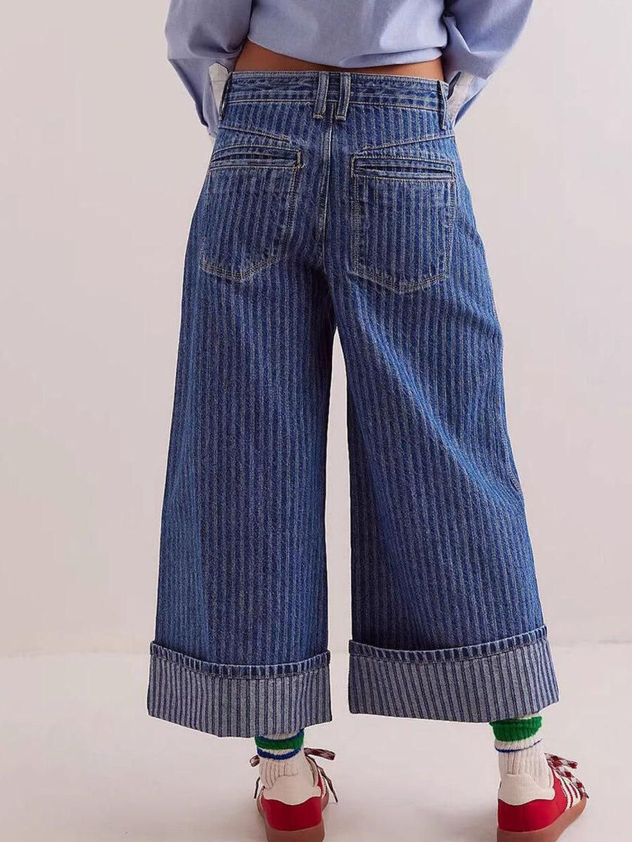 Wide-leg blue jeans worn by a person on a light background