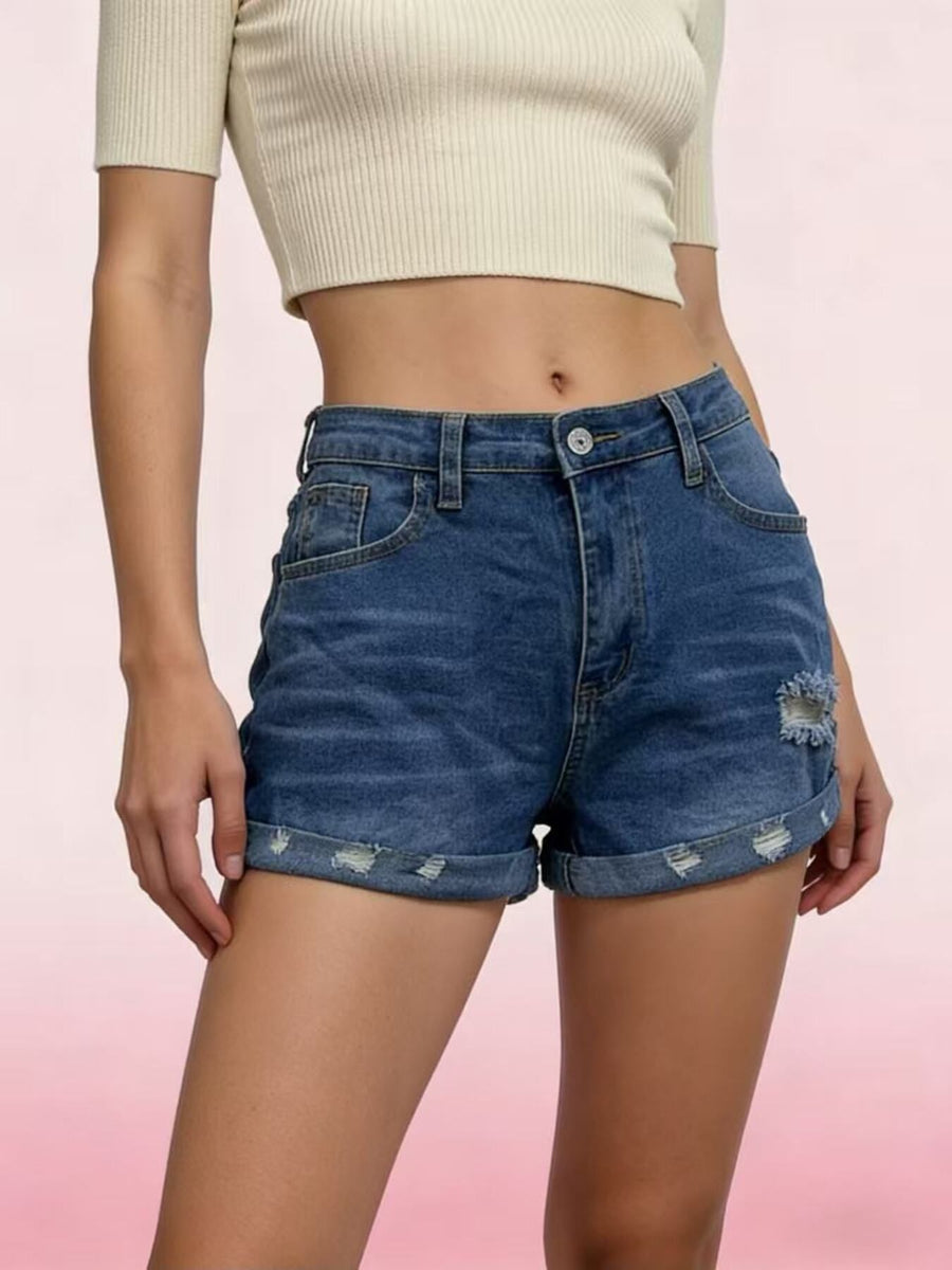 Person wearing blue denim shorts on a pink background