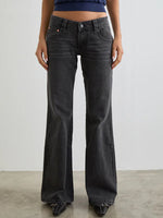 Person wearing black flared jeans against a plain background