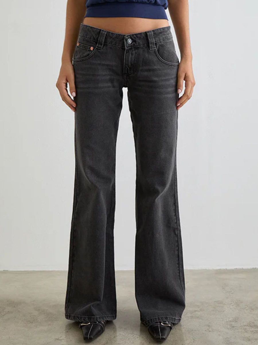 Person wearing black flared jeans against a plain background