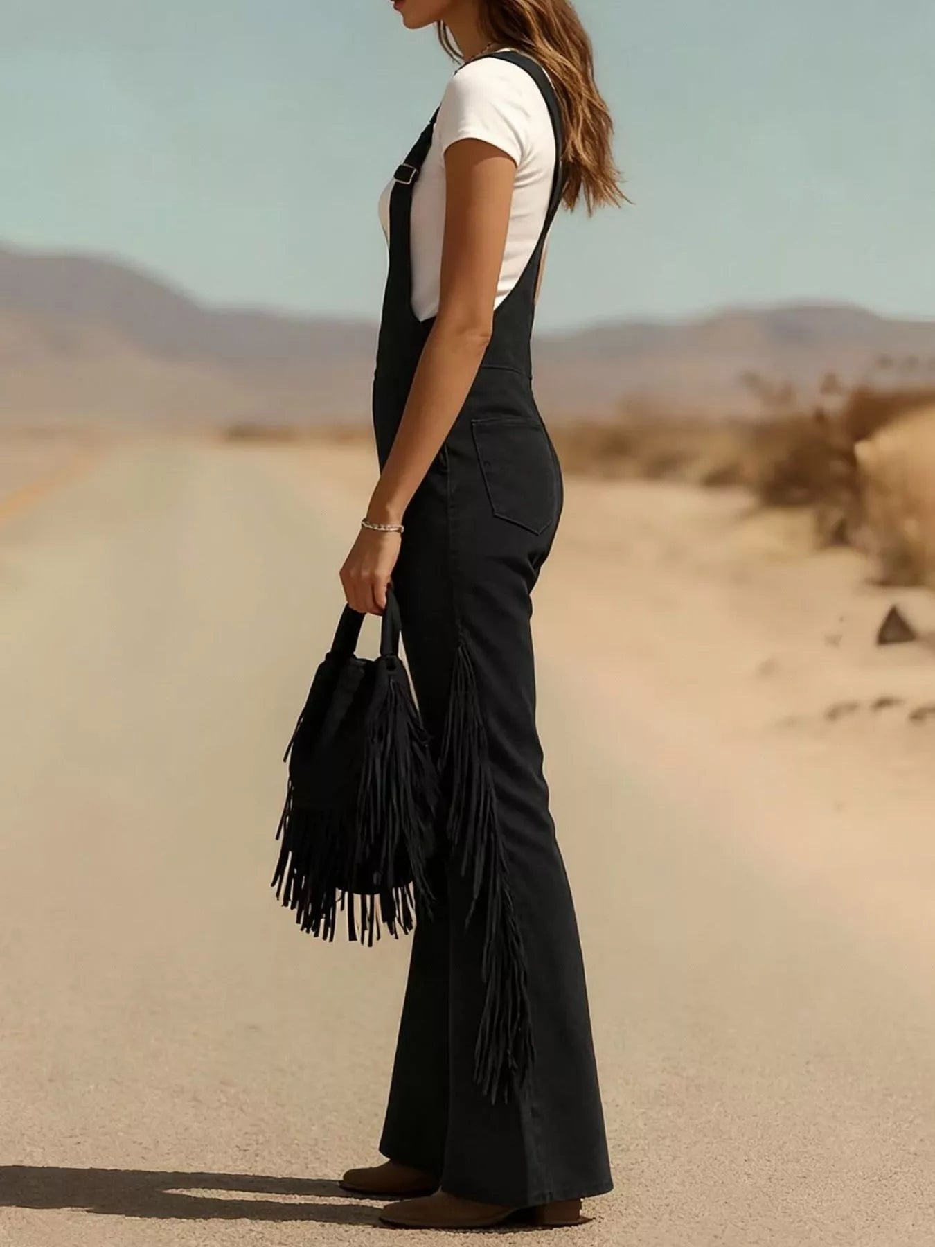 Person wearing a black fringe overalls outfit in a desert setting