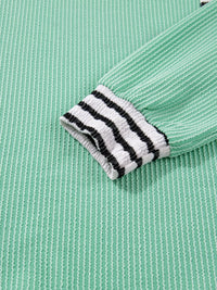 Close-up of a green fabric with a black and white striped band