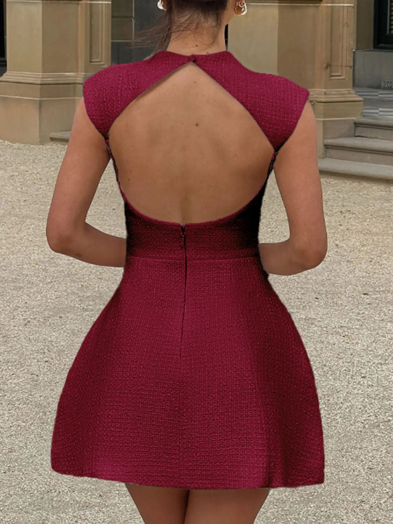 Red dress with open back worn by a person, standing in an outdoor setting.