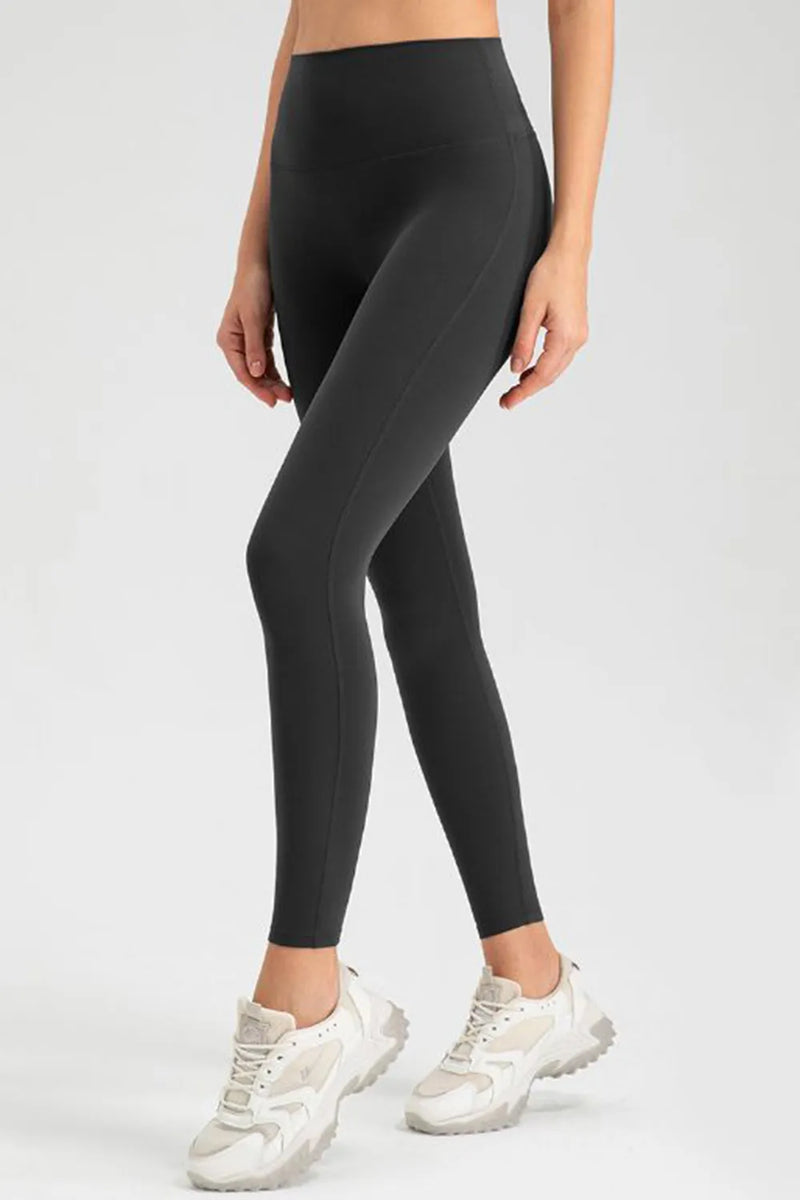 Person wearing black leggings and white sneakers on a light gray background