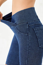 Close-up of blue jeans being pulled up on a person against a white background