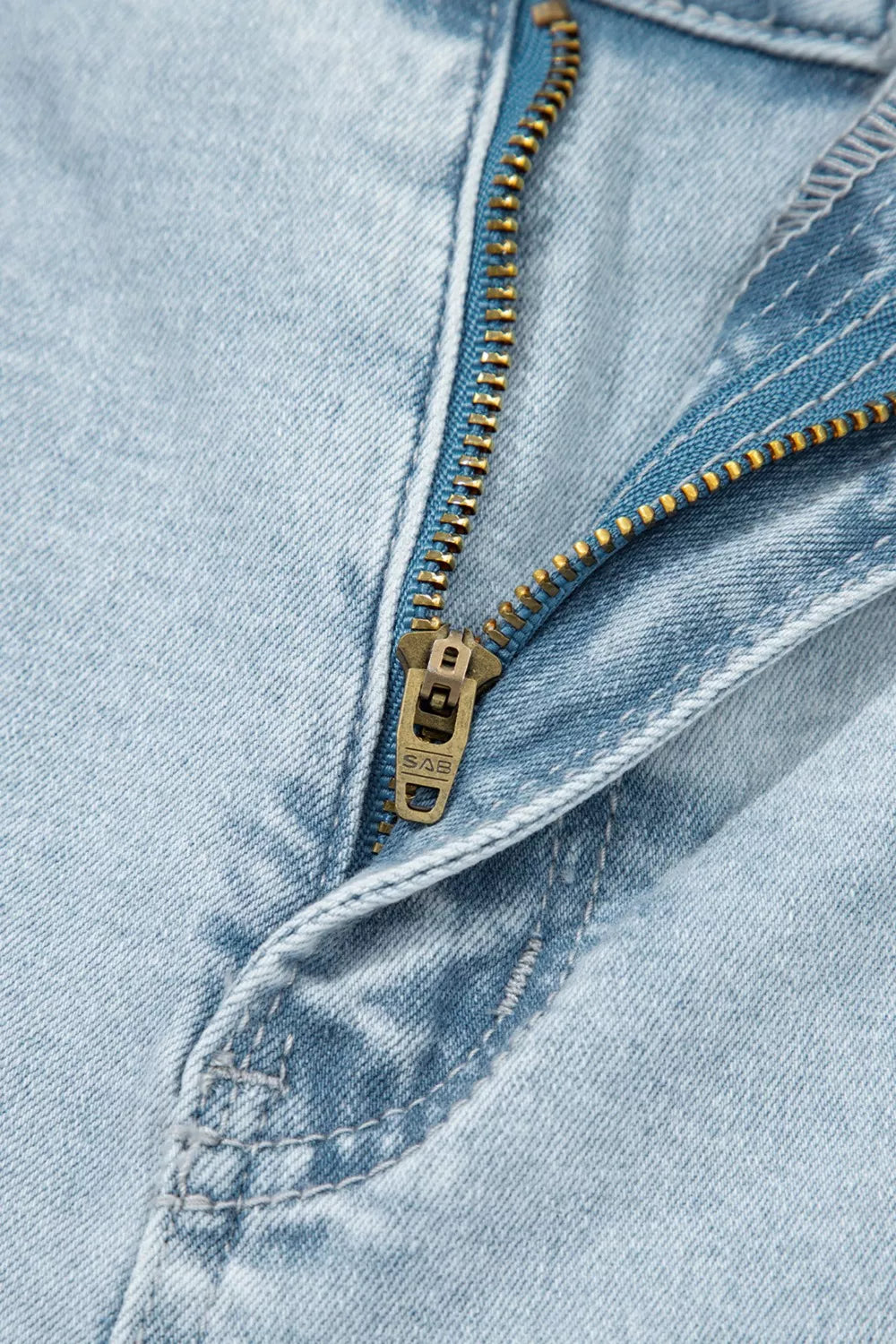 Close-up of a zipper on a pair of light blue jeans