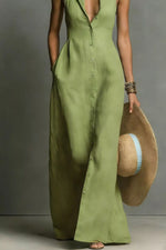 Person wearing a green dress holding a straw hat against a gray background