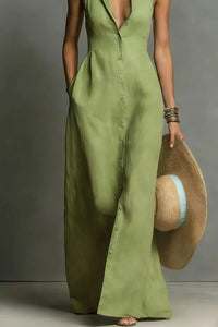 Person wearing a green dress holding a straw hat against a gray background