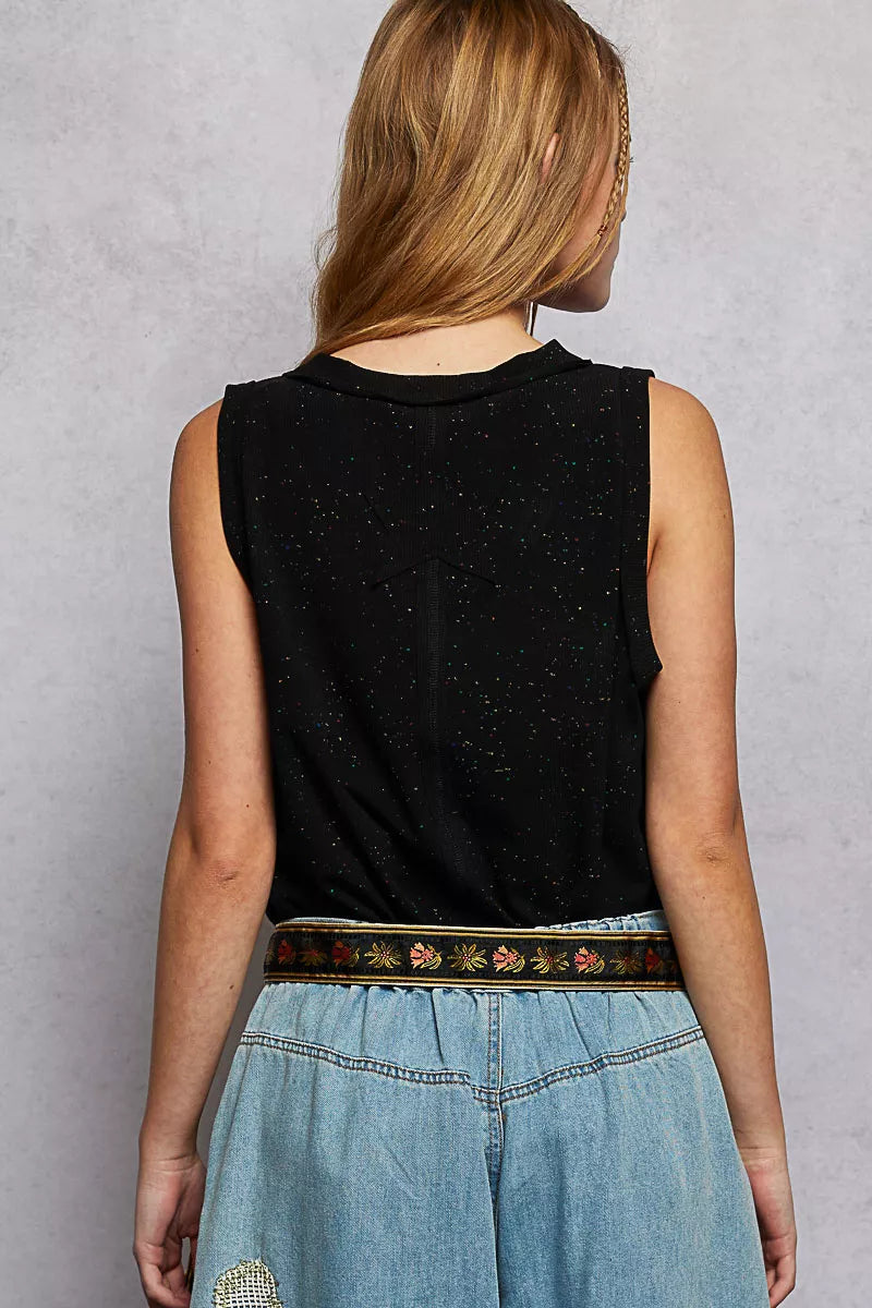 Person wearing a black sleeveless top and blue denim skirt with a patterned belt on a gray background