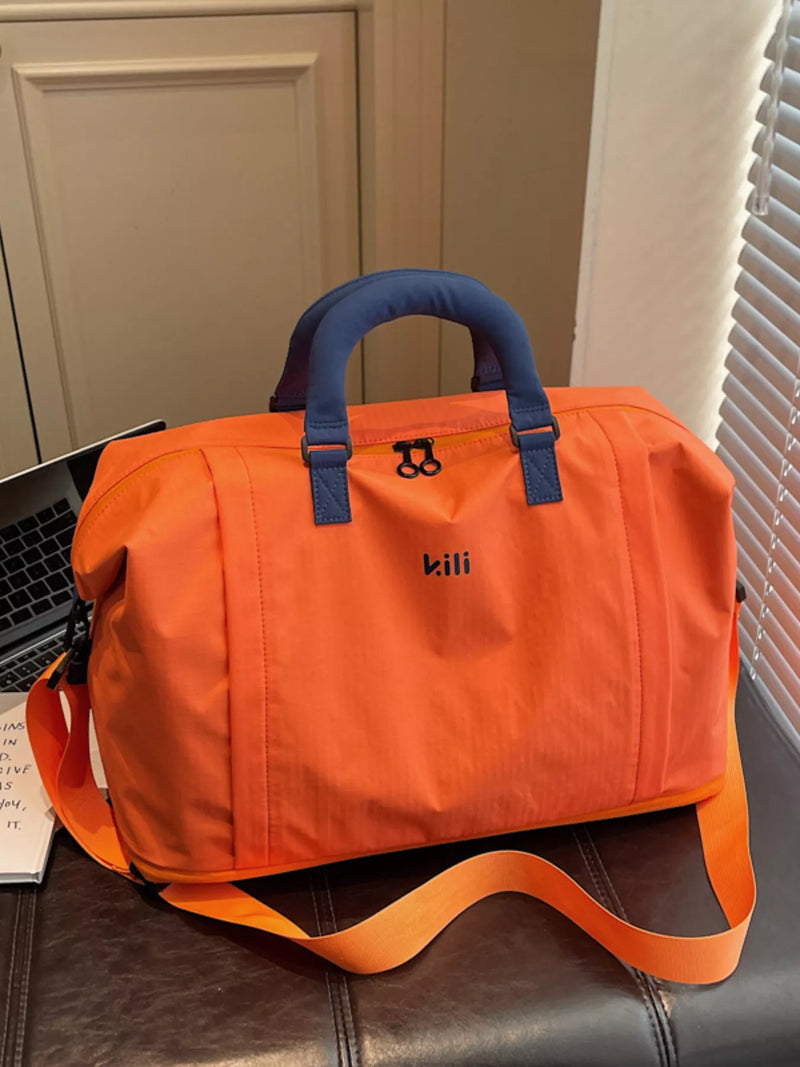 Orange duffel bag with blue handles on a leather surface