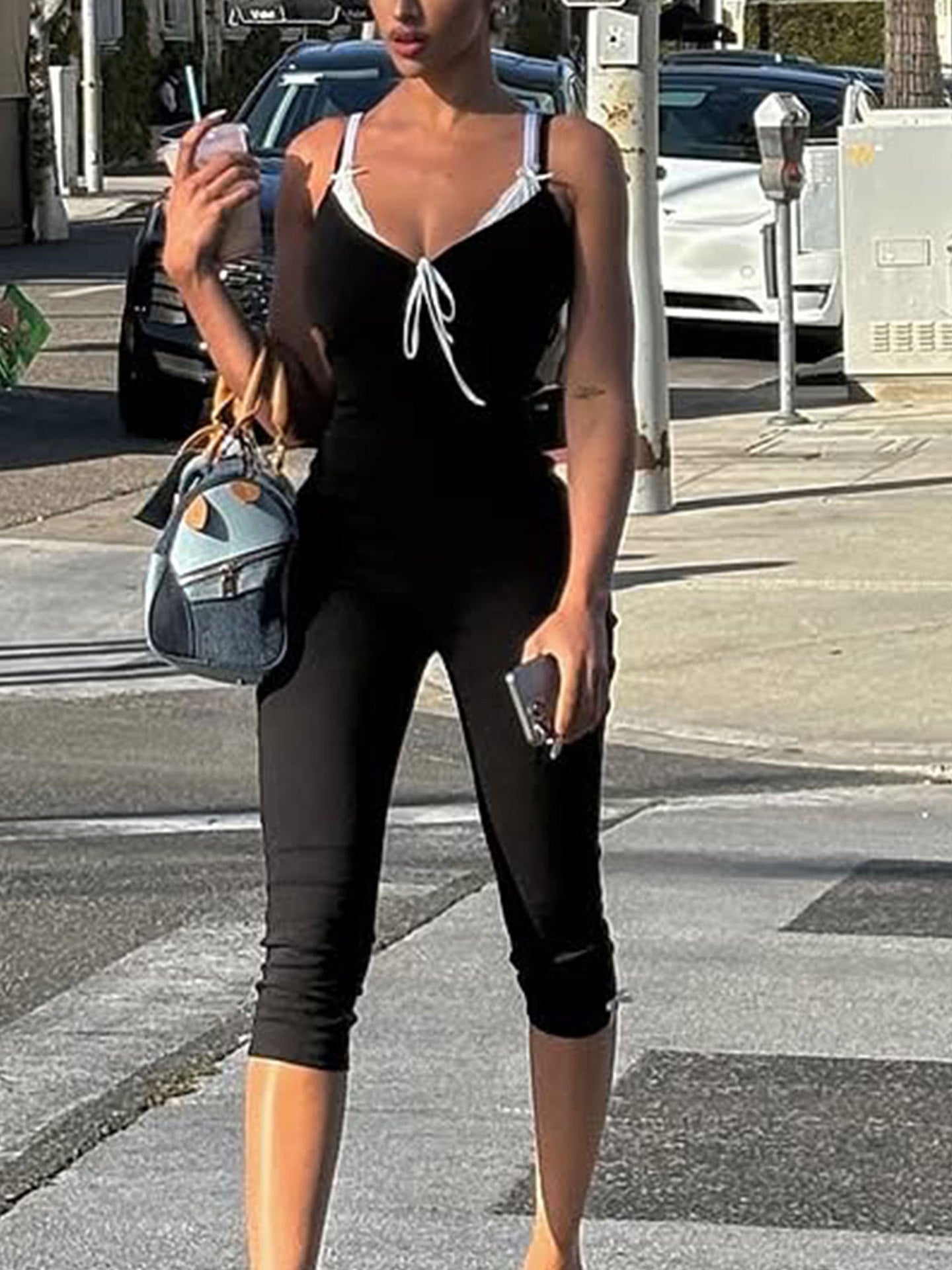 Person wearing a black athletic outfit with white accents on a city street.