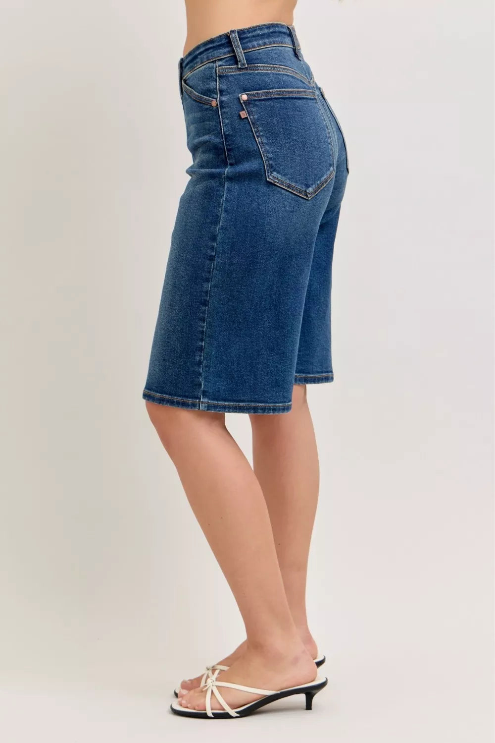 Blue denim shorts worn by a person on a plain background