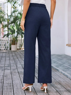 Navy blue wide-leg pants worn by a person on a wooden deck.