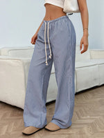 Person wearing blue and white striped pants with a drawstring in a living room setting.