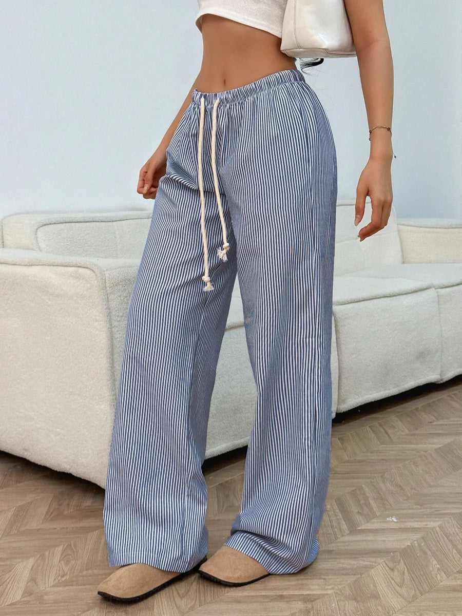 Person wearing blue and white striped pants with a drawstring in a living room setting.