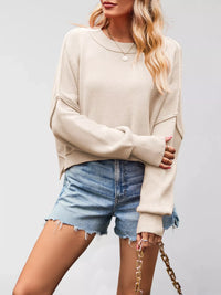 Woman wearing a beige sweater and denim shorts on a plain background