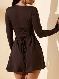 Black long-sleeve dress with a tie waist on a plain background