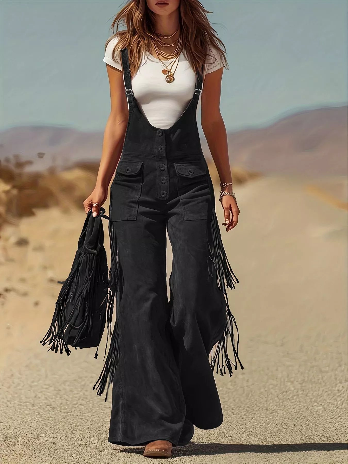 Person wearing black fringed overalls and white top in a desert setting