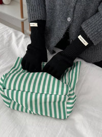 Person wearing black gloves with white labels on a green and white striped cushion.
