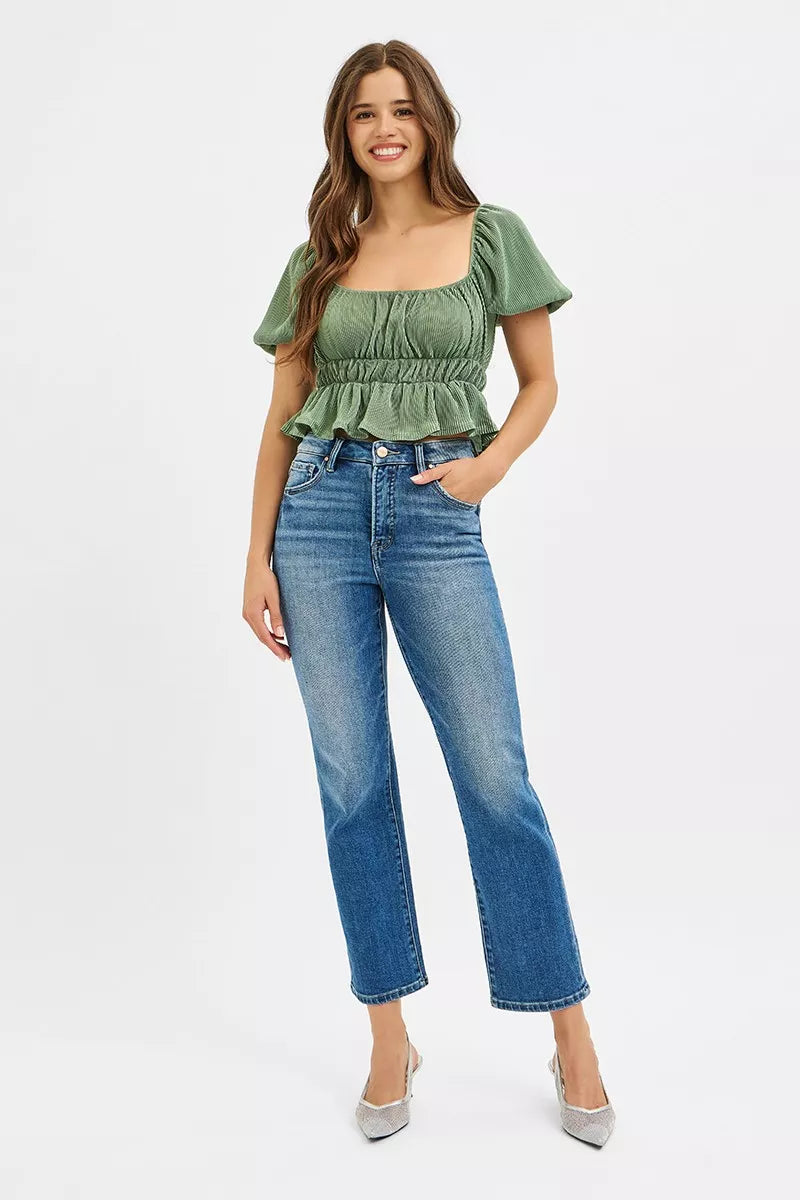 Woman wearing a green top and blue jeans on a white background