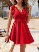Woman in a red dress standing by a pool with palm trees in the background