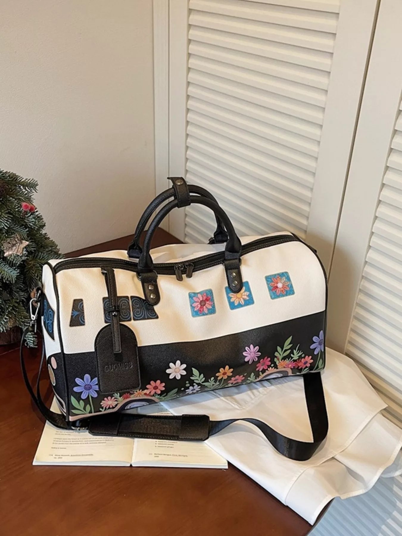 White duffel bag with floral patterns on a wooden surface