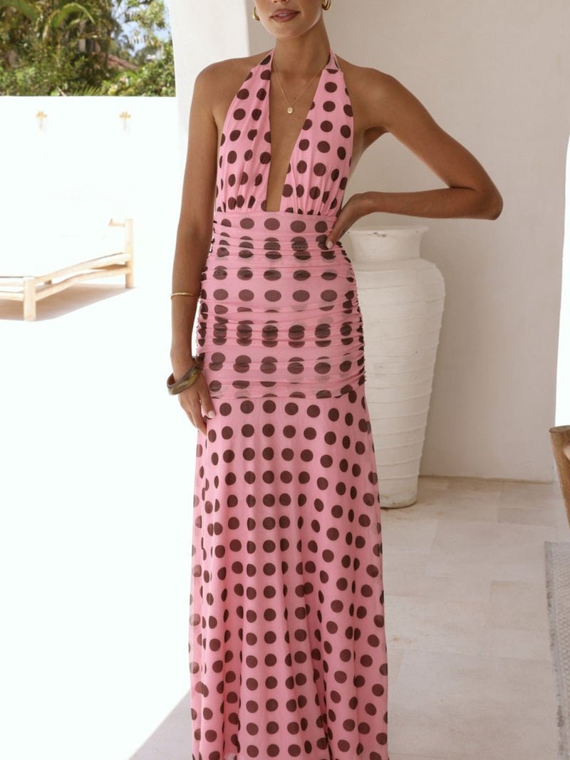 Woman wearing a pink polka dot dress standing in an outdoor setting.