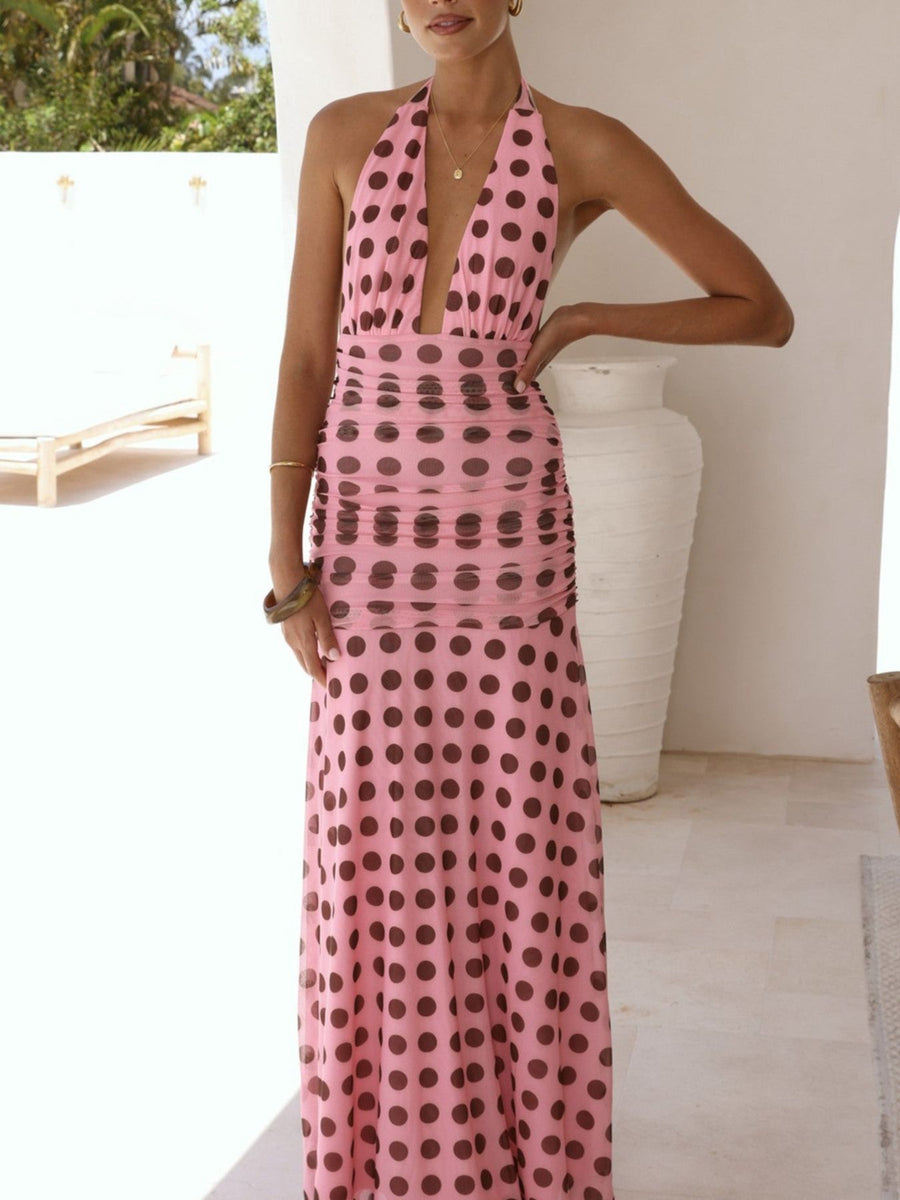Woman wearing a pink polka dot dress standing in an outdoor setting.