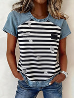 Person wearing a black and white striped shirt with denim sleeves on a plain background