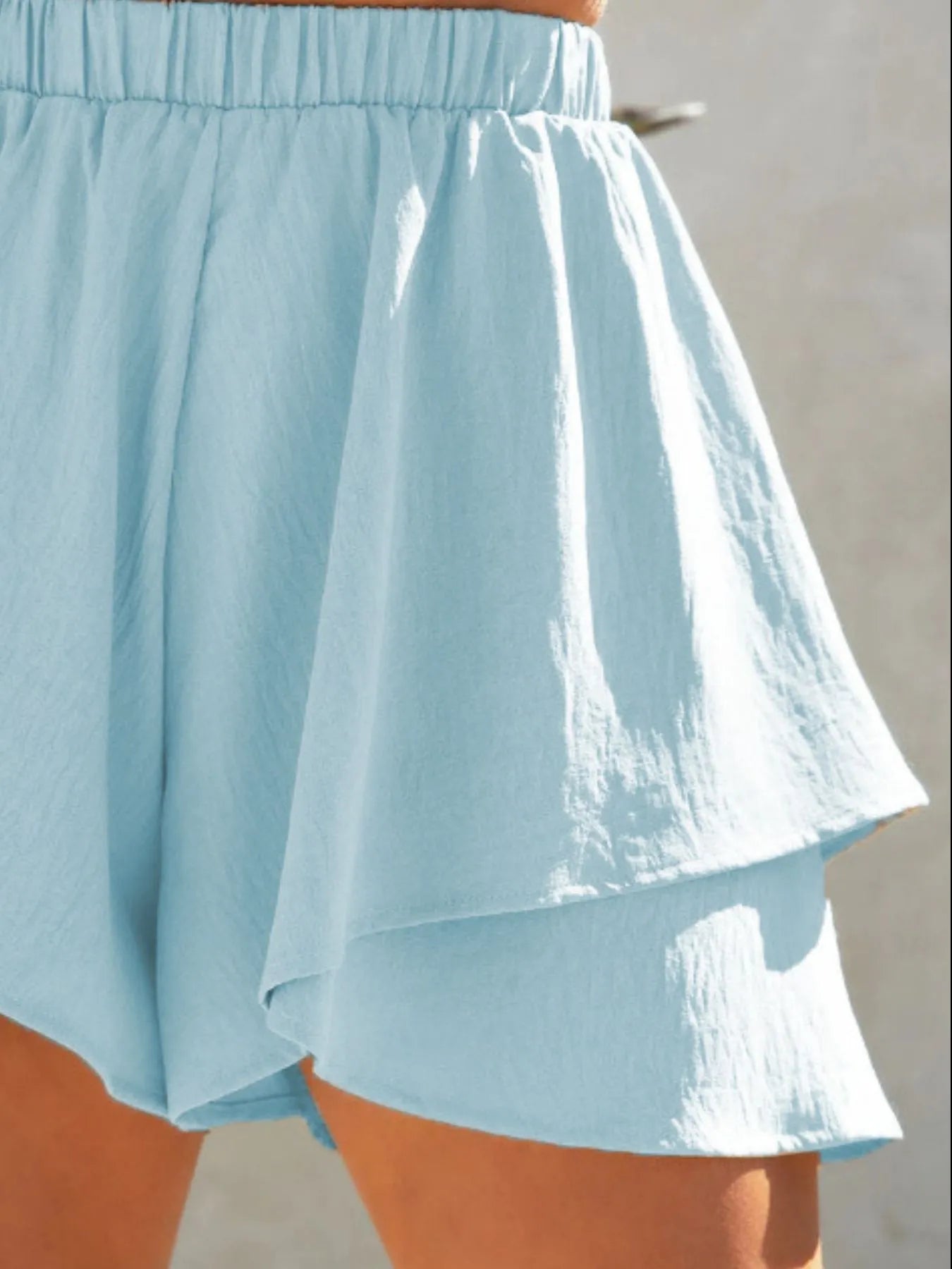 Light blue shorts with a white layer worn by a person against a neutral background