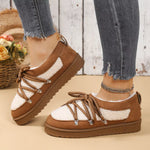 Brown and white sneakers with a fluffy interior worn by a person on a wooden floor.