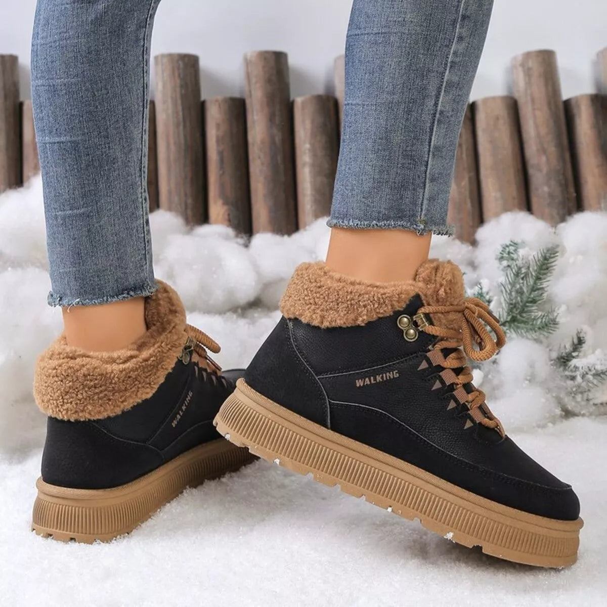 Black winter boots with brown fur lining worn by a person in a snowy setting.