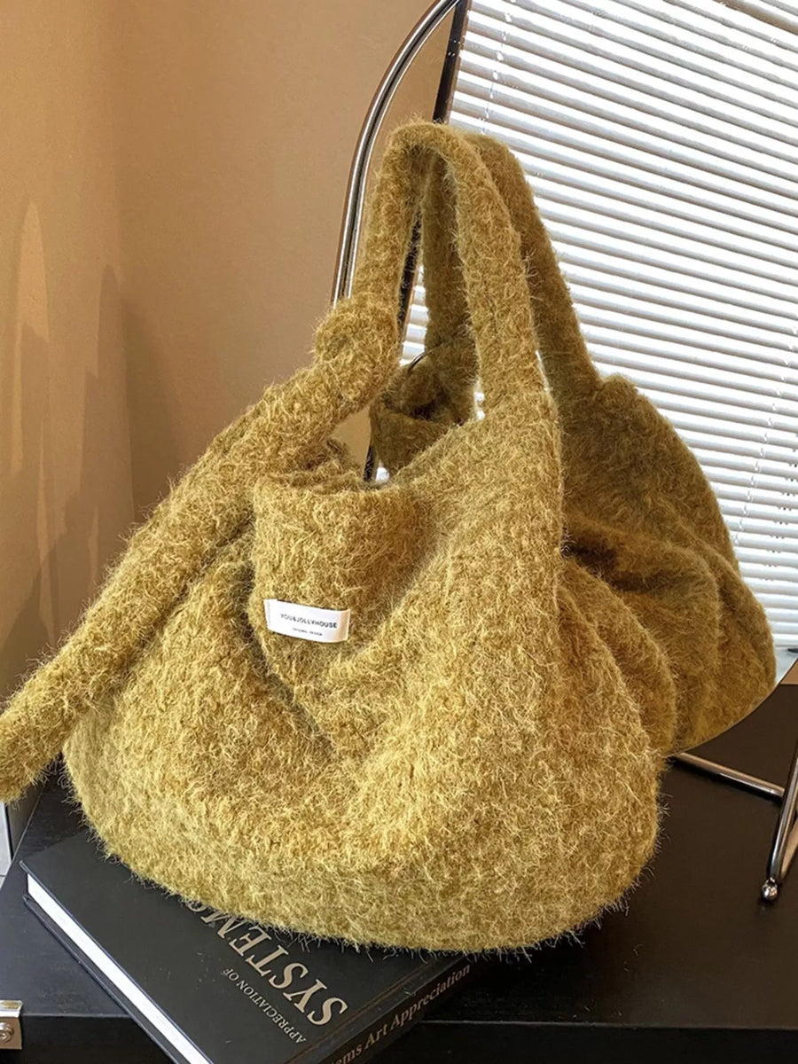 Yellow textured handbag on a black surface with a blurred background