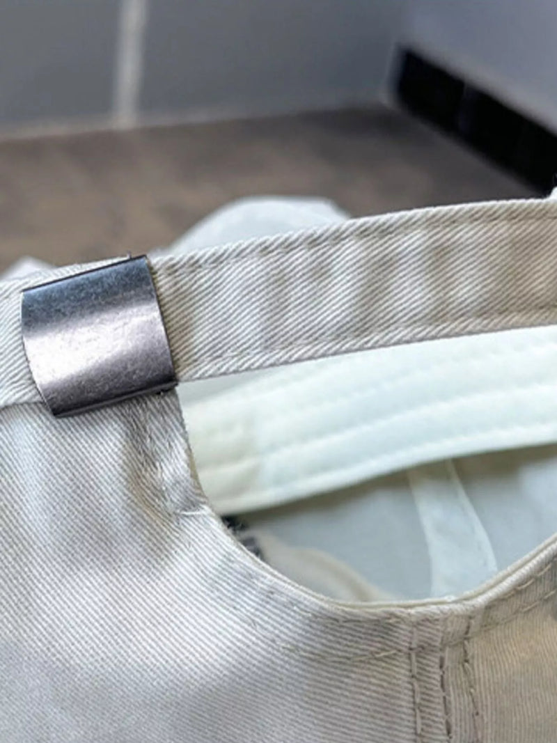 Close-up of a beige cap with a metallic buckle on a blurred background