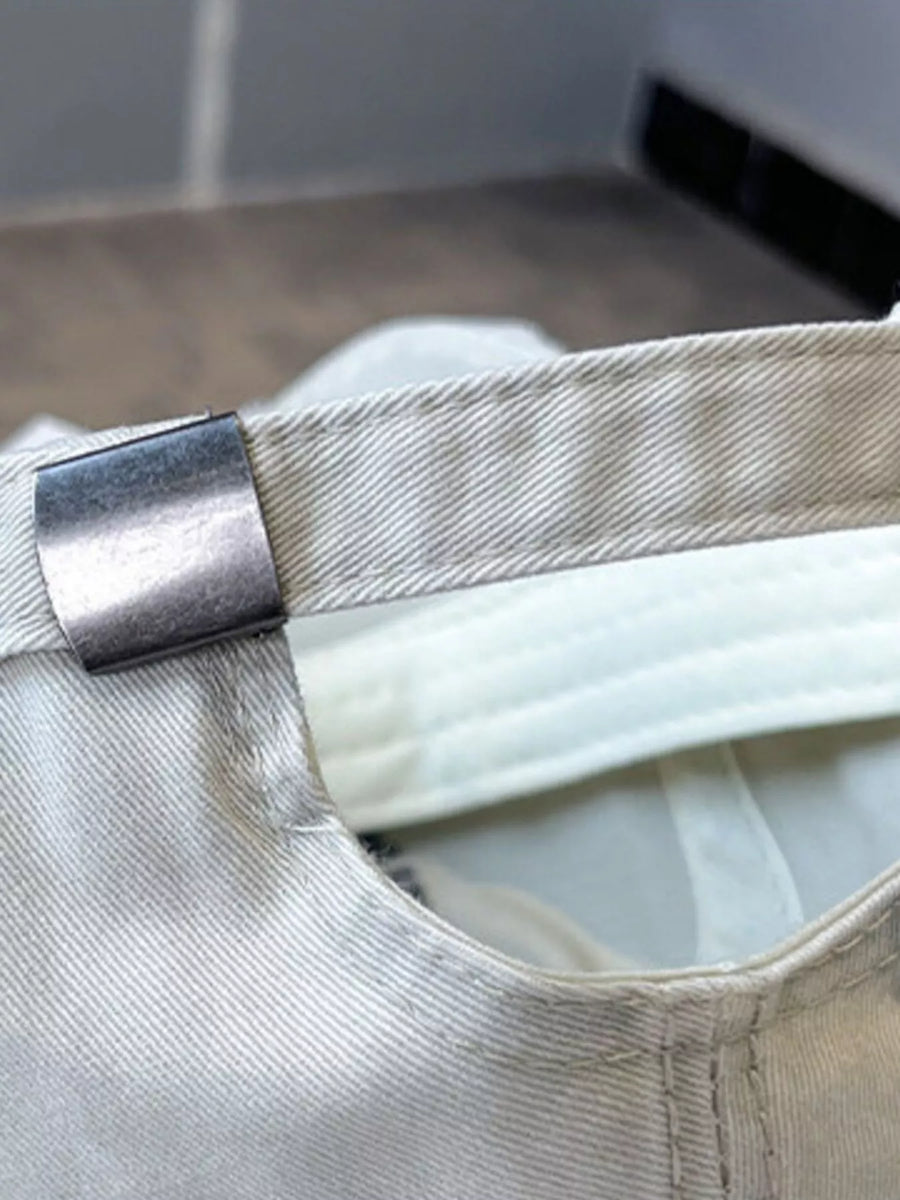 Close-up of a beige cap with a metallic buckle on a blurred background