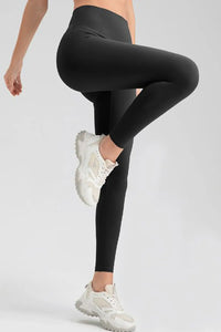 Person wearing black leggings and white sneakers on a light gray background