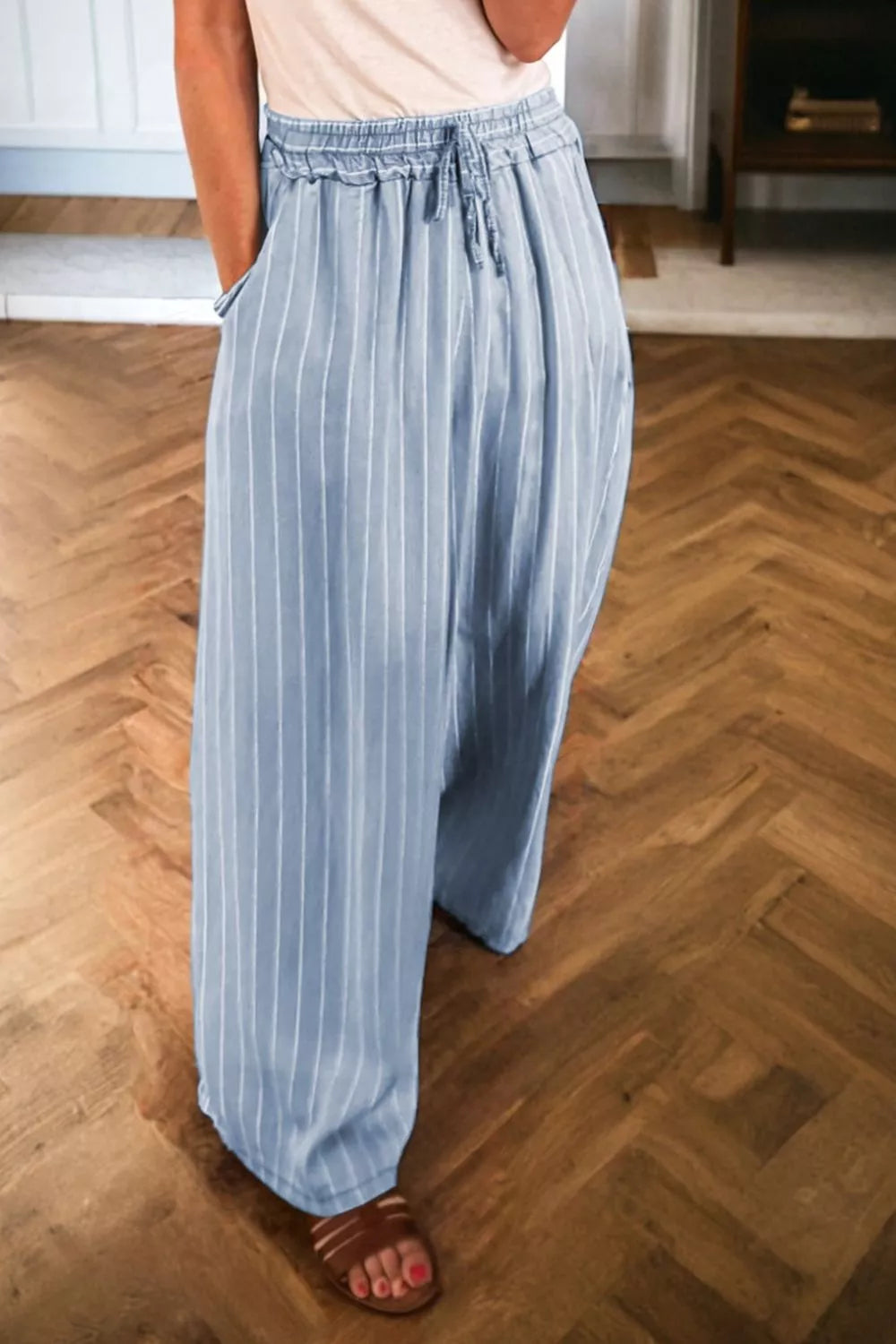 Light blue striped pants worn by a person on a wooden floor.
