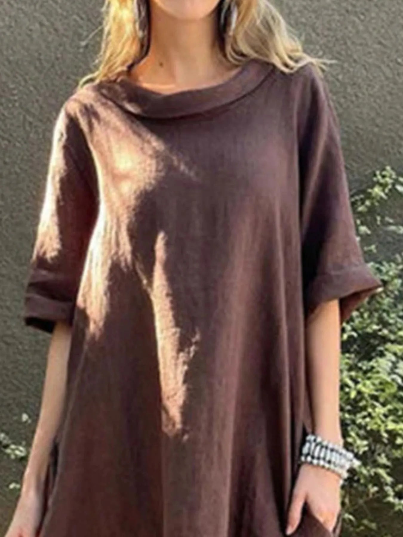 Person wearing a brown tie-dye t-shirt against a green outdoor background