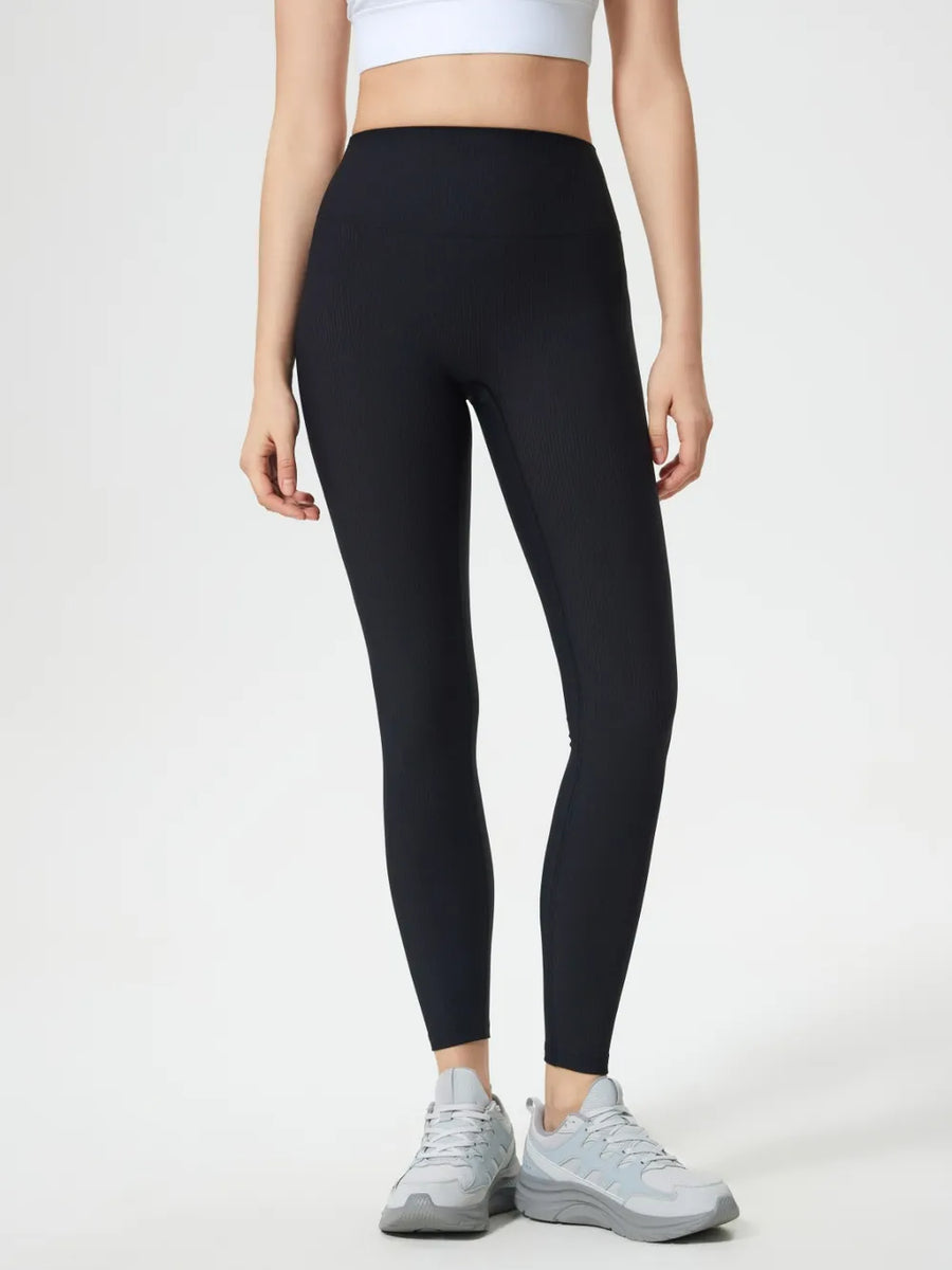 Person wearing black leggings and white sneakers on a white background