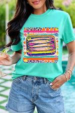 Person wearing a teal t-shirt with a colorful graphic design, standing by a pool.