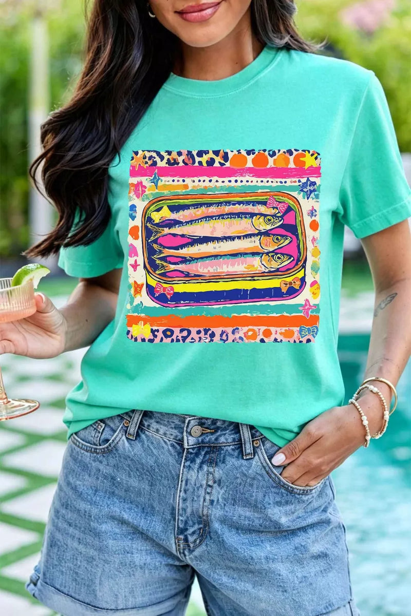 Person wearing a teal t-shirt with a colorful graphic design, standing by a pool.