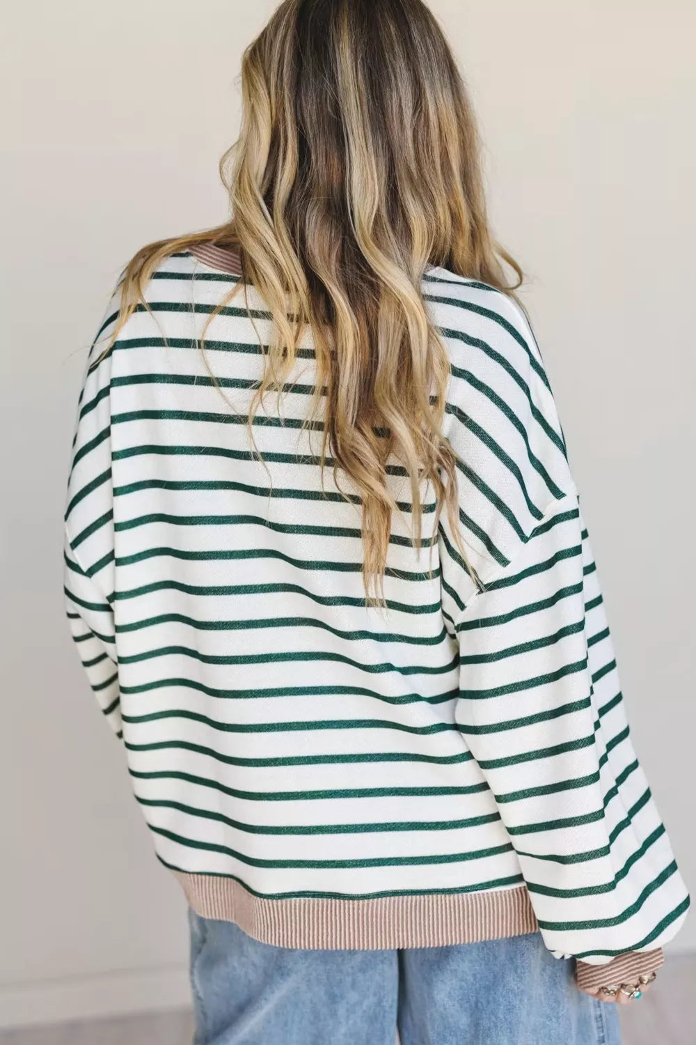 Person wearing a green and white striped sweater with a plain background