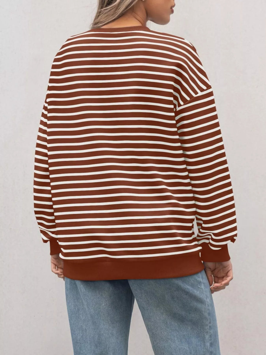 Person wearing a brown and white striped sweater with light blue jeans against a plain background