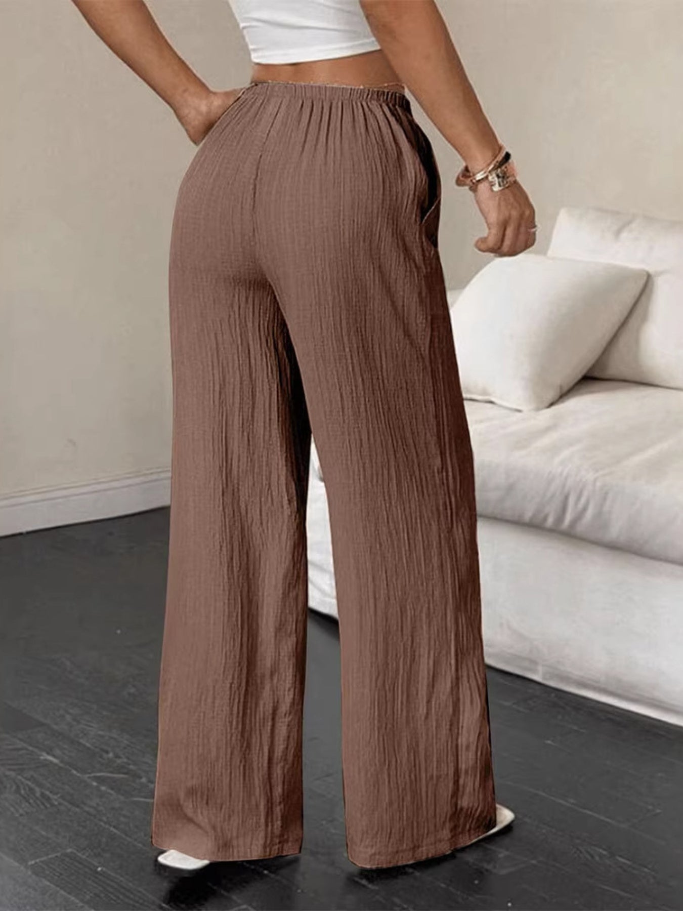 Person wearing brown wide-leg pants in a living room setting