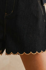 Black shorts with scalloped edge on a neutral background