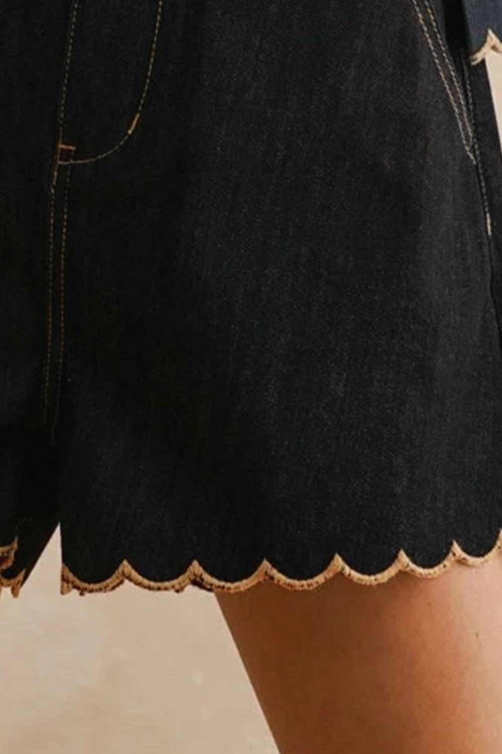 Black shorts with scalloped edge on a neutral background