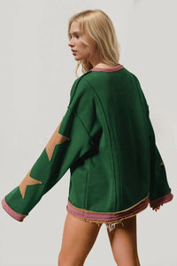 Woman wearing a green sweater with star patterns on a plain background