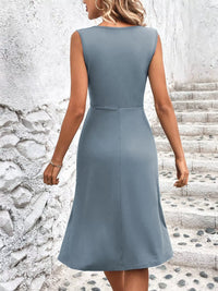 Woman wearing a light blue dress standing on stone steps with a textured wall background