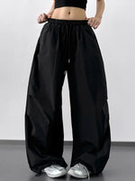 Person wearing loose black pants on a plain background