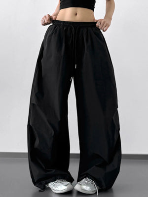 Person wearing loose black pants on a plain background